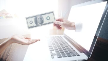 hand coming out of a computer screen handing a dollar bill to another hand
