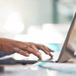 hands typing on a laptop keyboard