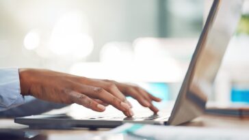 hands typing on a laptop keyboard