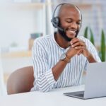 smiling man with headset using a laptop