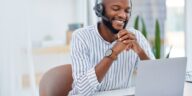 smiling man with headset using a laptop