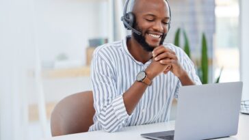 smiling man with headset using a laptop