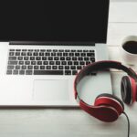headphones on a laptop next to a mug of coffee