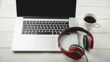 headphones on a laptop next to a mug of coffee