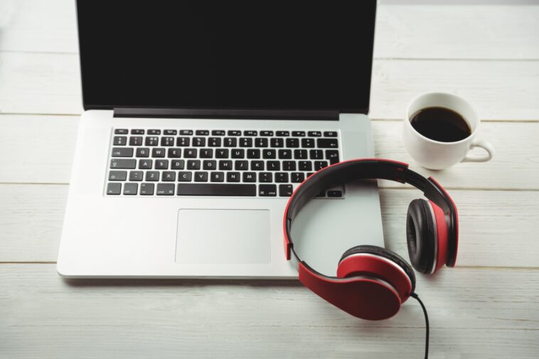 headphones on a laptop next to a mug of coffee