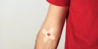 man's arm with a double plaster and a heart on his veins