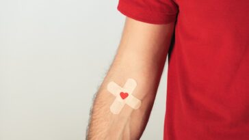 man's arm with a double plaster and a heart on his veins