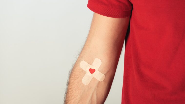 man's arm with a double plaster and a heart on his veins
