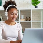 woman with headphones working on a laptop from home