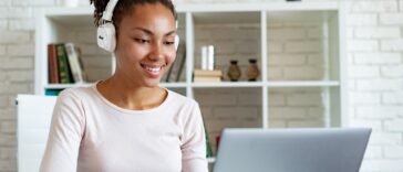 woman with headphones working on a laptop from home