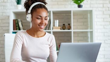 woman with headphones working on a laptop from home