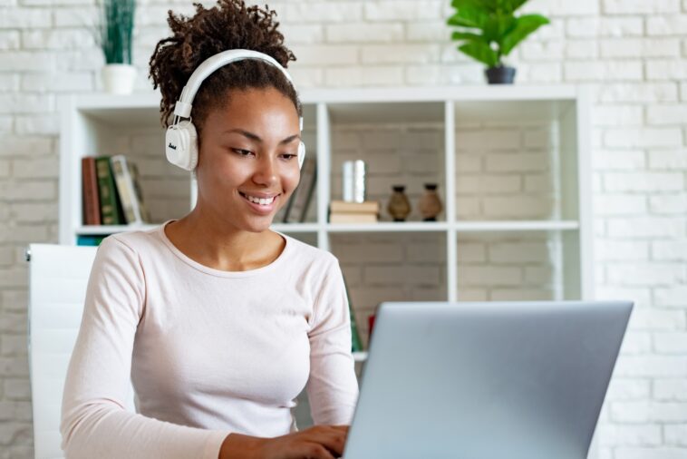 woman with headphones working on a laptop from home