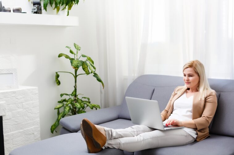 woman working on a laptop while sitting on a couch