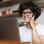 woman talking on the phone looking at a computer