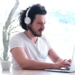 man with headphones using a laptop from home