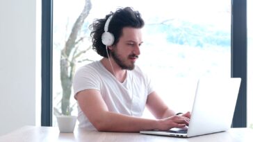 man with headphones using a laptop from home