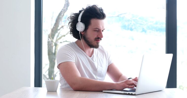 man with headphones using a laptop from home