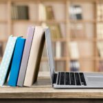 stack of books leaning on a laptop