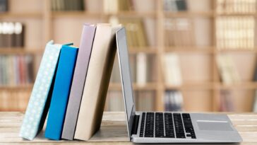stack of books leaning on a laptop