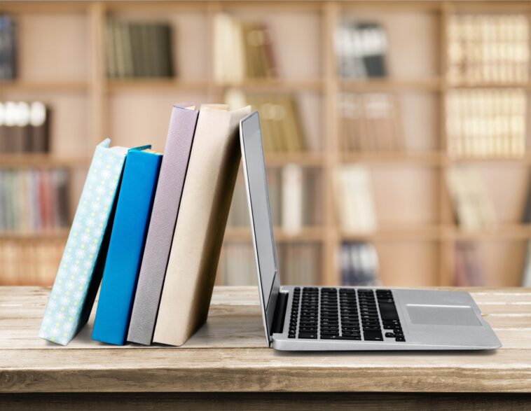 stack of books leaning on a laptop
