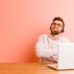 man with headset working on a laptop from home