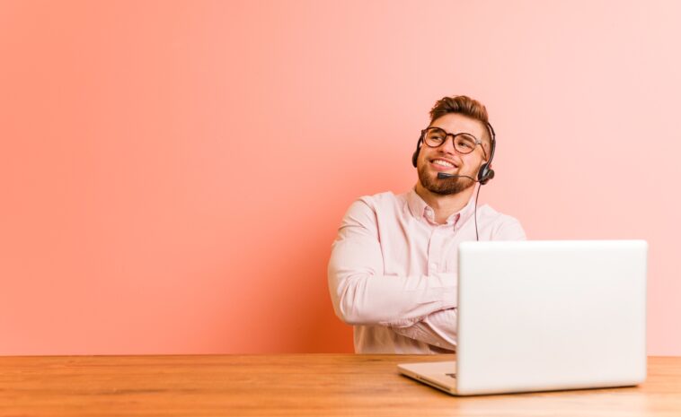 man with headset working on a laptop from home