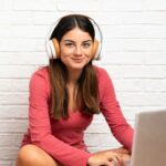 woman with headphones working on a laptop sitting on the floor