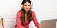 woman with headphones working on a laptop sitting on the floor