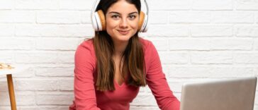 woman with headphones working on a laptop sitting on the floor