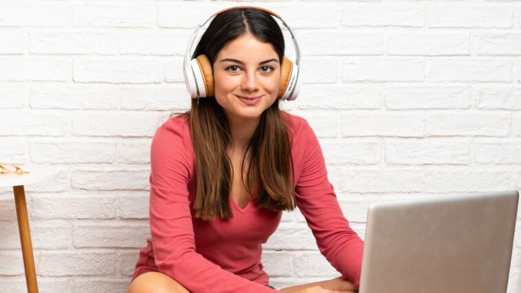 woman with headphones working on a laptop sitting on the floor