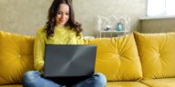 girl working from home on a couch with a laptop in her lap