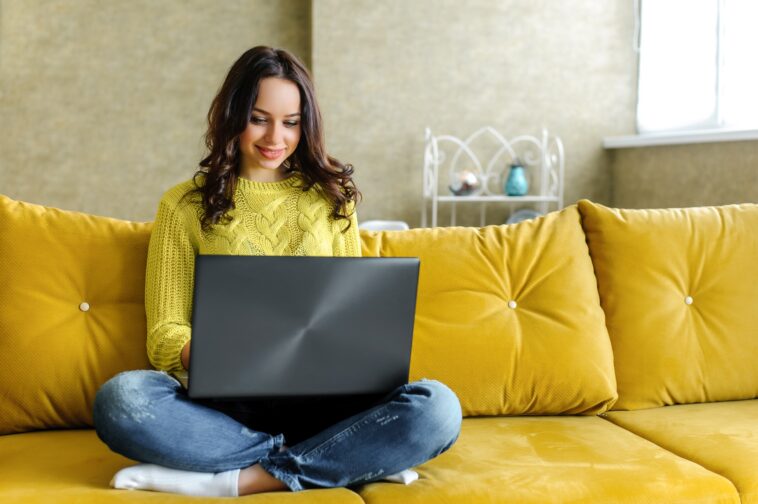 girl working from home on a couch with a laptop in her lap