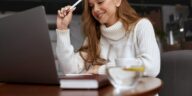 woman holding a pen looking at a laptop