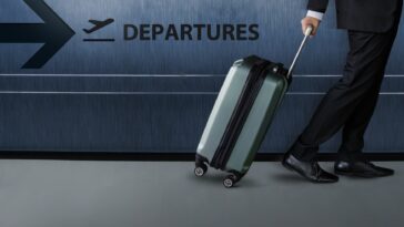 businessman with luggage walking inside an airport terminal