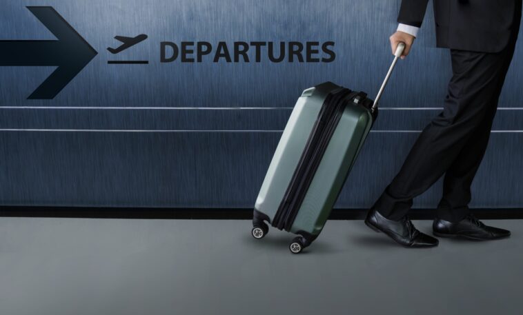 businessman with luggage walking inside an airport terminal