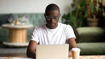 man sitting at a desk working on a laptop