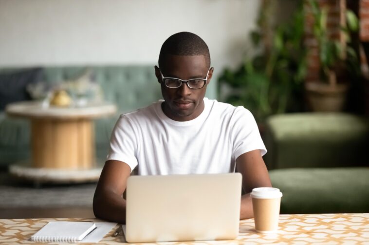 man sitting at a desk working on a laptop