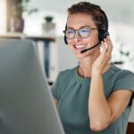 smiling woman with headset working on a computer from home