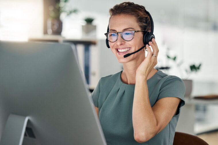 smiling woman with headset working on a computer from home