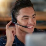 smiling man with a headset working as an agent from home