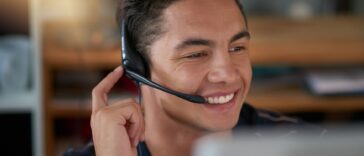smiling man with a headset working as an agent from home