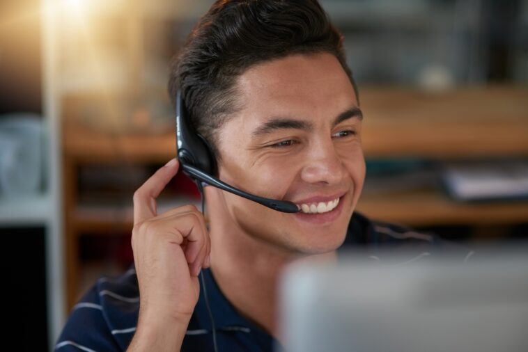 smiling man with a headset working as an agent from home