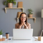 smiling woman working on a laptop from a home office