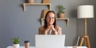 smiling woman working on a laptop from a home office