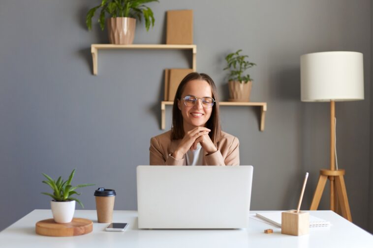 smiling woman working on a laptop from a home office