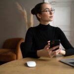 woman with glasses working from home with a laptop and smartphone