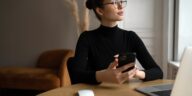 woman with glasses working from home with a laptop and smartphone