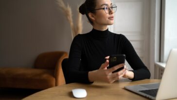 woman with glasses working from home with a laptop and smartphone