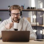 man holding a mug and working on a laptop at home