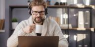 man holding a mug and working on a laptop at home